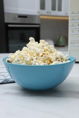 Tasty popcorn in bowl n on white marble table indoors