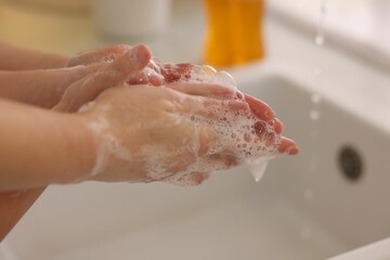 Fototapeta premium Mother and daughter washing their hands indoors, closeup