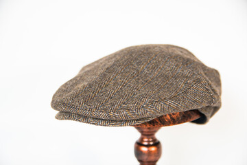 Concept photo of a scally cap or flat cap made of khaki herringbone tweed fabric mounted on a...