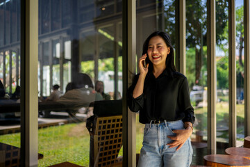 A woman is talking on her cell phone while standing in front of a window