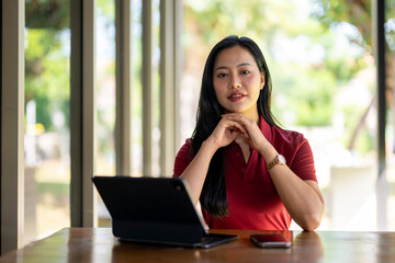 A woman sits at a table with a laptop and a cell phone