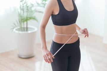 ウエストのサイズを測る女性