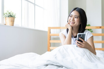 スマホを持って窓の外を眺める女性