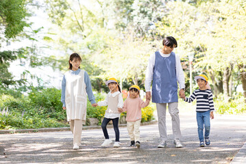 公園を散歩する保育士と園児