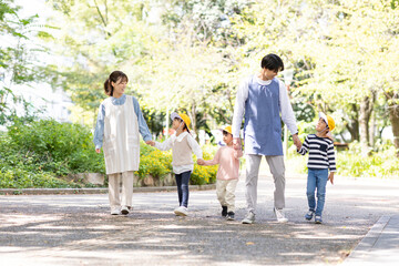 Obraz premium 公園を散歩する保育士と園児