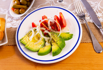 Olives, bran bread and glass of red wine are served with salad of red tomatoes, avocado and white onions. Festive dish serving, eating out, concept of tasty, healthy, healthy varied food