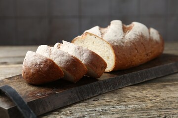 Cutting board with fresh bread on wooden table, closeup