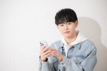 スマホを持つ若い20代の笑顔でタップする男性のカメラ目線　白背景