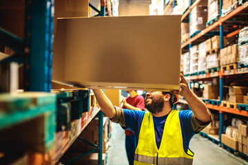 Smiling male warehouse worker organizing boxes in storage facility