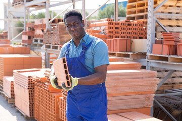 Portrait african american worker lays bricks in an open air warehouse