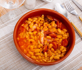 Dish of Spanish cuisine Alubias con chorizo, beans in tomato sauce with sausage chorizo served on ceramic plate
