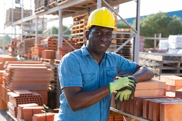 Construction shop worker stacks bricks on an open-air site
