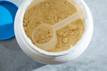 A view of a plastic measuring scoop inside a container of vegan protein powder.