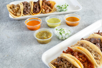 A view of a variety of salsas surrounded by assorted street tacos.