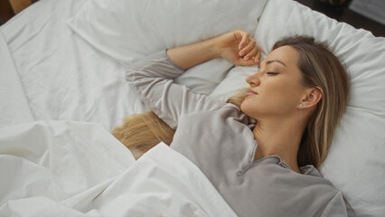 Woman relaxing peacefully in a cozy bedroom setting with a serene expression while resting in a softly lit home interior featuring a comfortable bed and natural light.