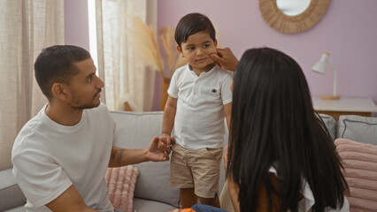 Fototapeta premium Latin family with man, woman, and child enjoying time together indoors in a cozy living room