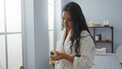 Woman examining beauty product in a serene spa room, wearing a white robe, with a calm and bright interior, capturing a peaceful wellness experience indoors