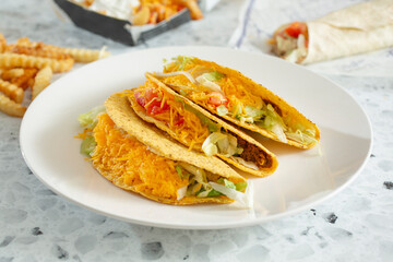 A view of three hard shell tacos on a plate.