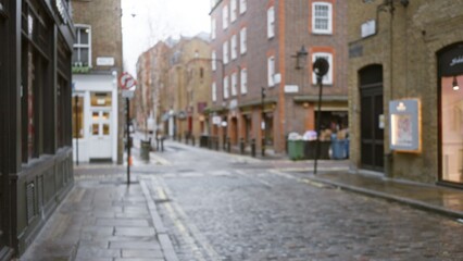 Blurred autumn street scene in london's seven dials, showcasing bokeh effects and historic architecture, with a focus on cobblestone paths and rainy uk weather.