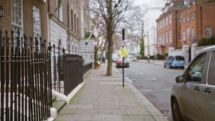 Blurred street scene in london captures winter atmosphere with defocused cars and trees, typical of urban uk with historic buildings lining the road.