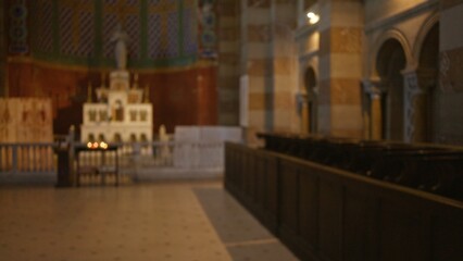 Fototapeta premium Blurred view of an ornate church interior with out-of-focus pews and bokeh lighting highlighting religious decor and architecture.