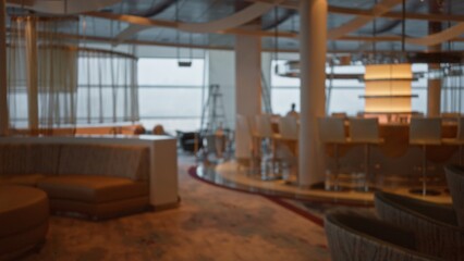 Defocused view of a luxury restaurant interior with chairs, tables, and ambient lighting, suggesting a modern, elegant venue for dining or relaxation.