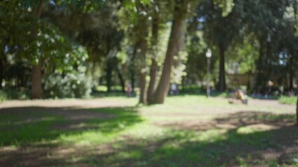 Blurred garden scene in villa borghese, rome with defocused trees capturing outdoor tranquility with soft natural lighting and bokeh effect.