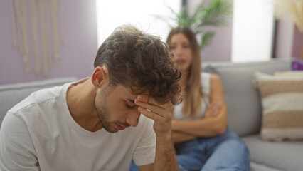 Man and woman sitting in living room having serious discussion, highlighting relationship challenges and emotions captured in a cozy indoor setting with neutral tones.