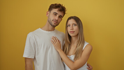 Couple posing affectionately over vibrant yellow background highlighting love and connection with man and woman embracing warmly in isolated close setting.