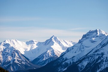 Obraz premium Scenic view of towering snow-covered mountains under a bright blue sky in winter, representing tranquility and the majesty of nature
