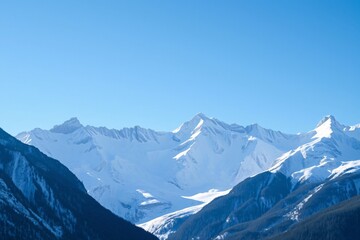 Obraz premium Scenic view of towering snow-covered mountains under a bright blue sky in winter, representing tranquility and the majesty of nature