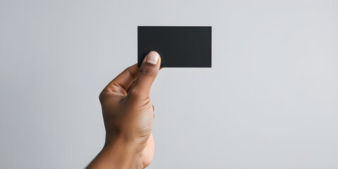 Hand of biracial man holding black business card on grey background, copy space, slow motion