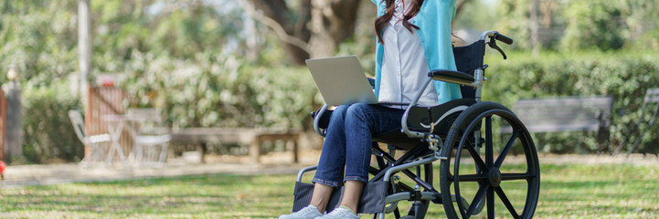 Obraz premium Young asian woman in wheelchair working with laptop