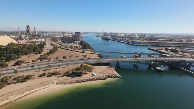 slow flight towards the port adelaide dockyard showing a bridge in the foreground with cars and trucks on it on a sunny day 4k 50p