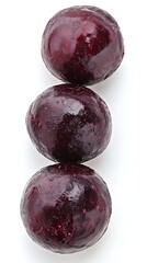 Frozen purple plums, stacked, white background, food close-up