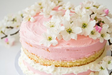 A sweet and elegant dessert featuring a pink cake with white flowers on top