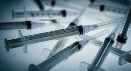 Close-up of medical syringes arranged on a reflective surface