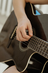Fototapeta premium Close-up of a young woman’s hands playing an acoustic guitar. The detailed shot captures the elegance, passion, and artistry of making music, evoking creativity and inspiration through the instrument