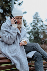 Smiling young woman walking through a frosty city street on a winter morning, talking on her...