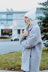 Smiling young woman walking through a frosty city street on a winter morning, talking on her...