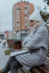 Smiling young woman walking through a frosty city street on a winter morning, talking on her...