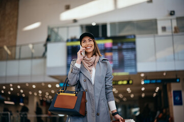 Happy woman communicating on mobile phone at departure terminal at airport.