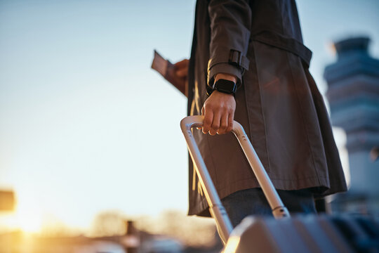 Close up of traveler with suitcase at airport at sunset.