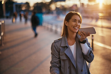 Happy traveler talking over her mobile phone's speaker while coming to airport terminal.