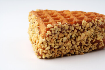Delicious triangular waffle coated with crushed nuts ready to be enjoyed as a sweet treat