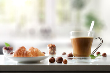 Coffee with hazelnut drink and pastries on table in kitchen