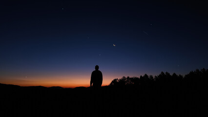 Silhouette of a man and countryside under the stars and Moonlight.
