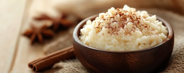 Delicious classic rice pudding topped with cinnamon on a rustic wooden table with warm beige accents