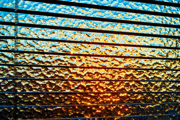 Nahaufnahme eines durchleuchteten Strukturglas, oder Ornamentglas mit orangenem und blauen...