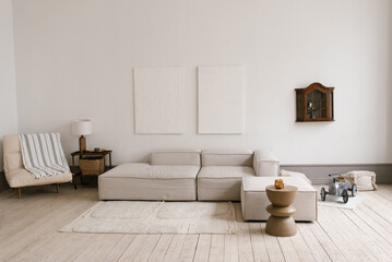 Scandinavian modern minimalistic living room with grey couch and armchair. Small table with lamp and toy car is on the floor